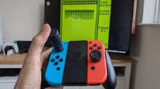 Nintendo Switch Joy-Cons in the hand of an adult featuring Thumb Soldier accessories